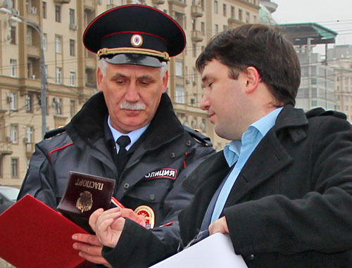 Сотрудник полиции проверяет документы у участника пикета. Москва, 18 октября 2013 г. Фото предоставлено участниками акции