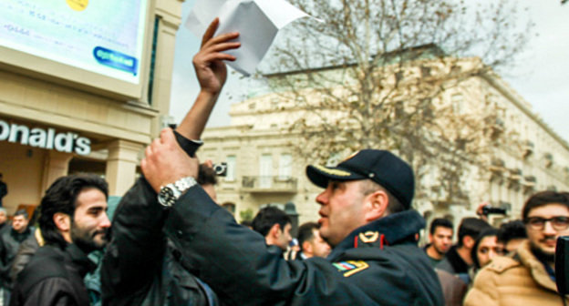 Баку, Площадь фонтанов, 8 декабря 2013 г. Полицейский препятствует проведению безмолвной акции против повышения цен на топливо. Фото Азиза Каримова для "Кавказского узла"