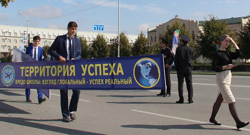 Ученик несет плакат с девизом школы. Фото Магомеда Магомедова для "Кавказского узла"