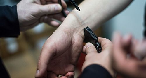 Сотрудник полиции одевает наручники. © Фото Елены Синеок, Юга.ру