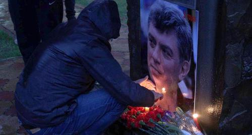 Участник акции в Сочи зажигает свечу памяти перед портретом Бориса Немцова, 27 февраля 2018 г. Фото: Светлана Кравченко для "Кавказского узла".