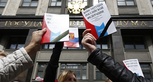Молодые люди держат в руках Конституцию России на фоне здания Госдумы. Фото: REUTERS/Sergei Karpukhin