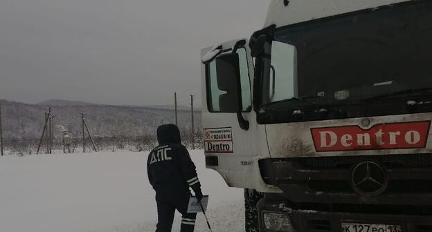 Сотрудник ДПС у большегрузного автомобиля в снегопад.  Фото УГИБДД ГУ МВД России 