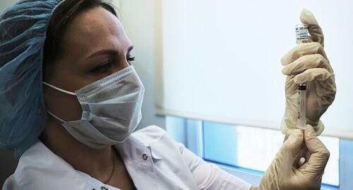 Медицинский работник держит в руках шприц и вакцину. Фото: REUTERS/Eduard Korniyenko