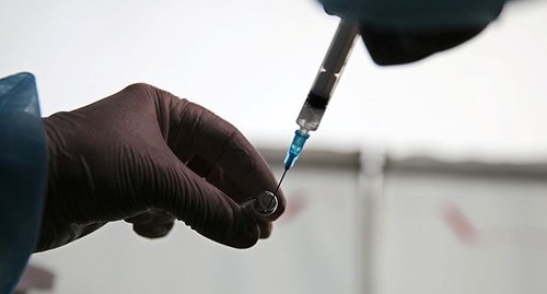 Медицинский работник держит шприц и вакцину "Спутник V". Фото: REUTERS/Evgeny Kozyrev
