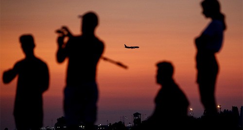 Туристы на берегу моря на фоне ночного города и пролетающего самолета. Сочи, май 2021 г. Фото: REUTERS/Maxim Shemetov