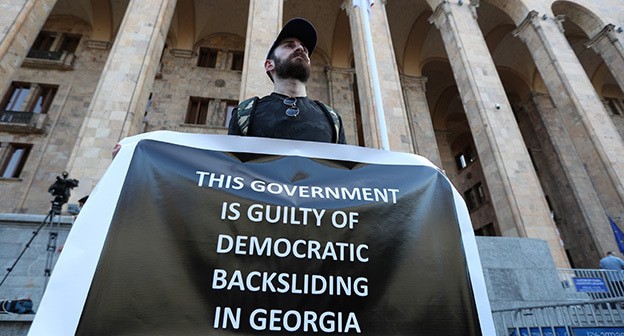 Активист держит плакат на митинге с требованием отставки премьер-министра и правительства после смерти оператора, избитого на прошлой неделе во время насилия против активистов ЛГБТ. Тбилиси, 17 июля 2021 года. Фото: REUTERS/Irakli Gedenidze