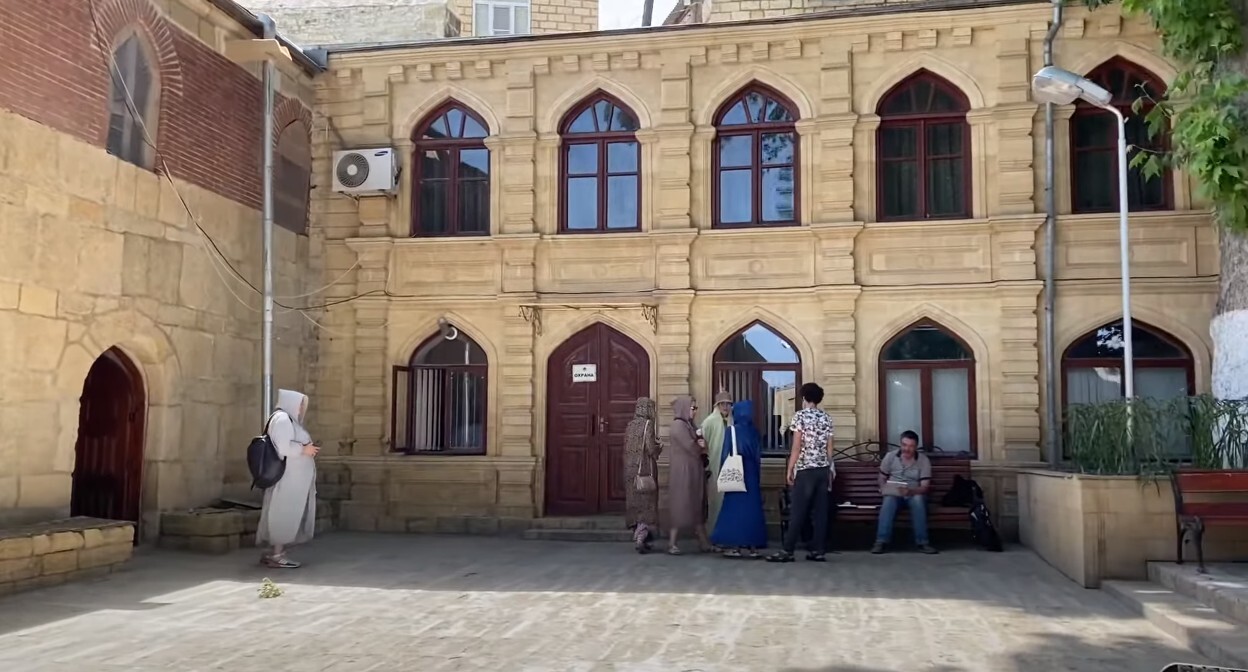 Туристы во дворе мечети в Дербенте. Стоп-кадр из видео https://www.youtube.com/watch?v=1rUg3LrF6kQ